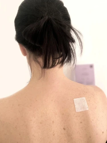 Plaster przeciwbólowy BioBloom CBD na plecach kobiety, miejscowa ulga bólu mięśni
